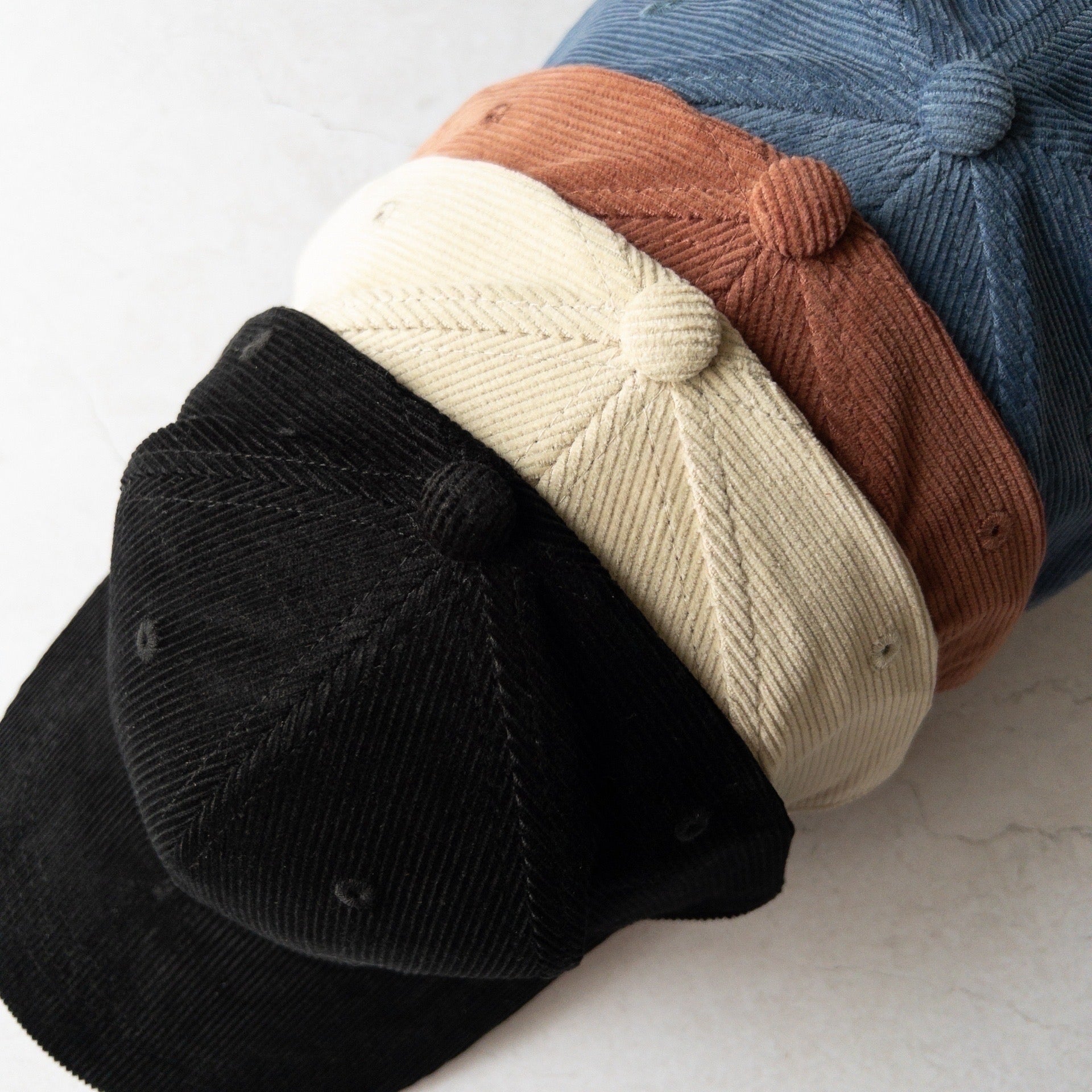 Four different coloured hats stacked on a light background